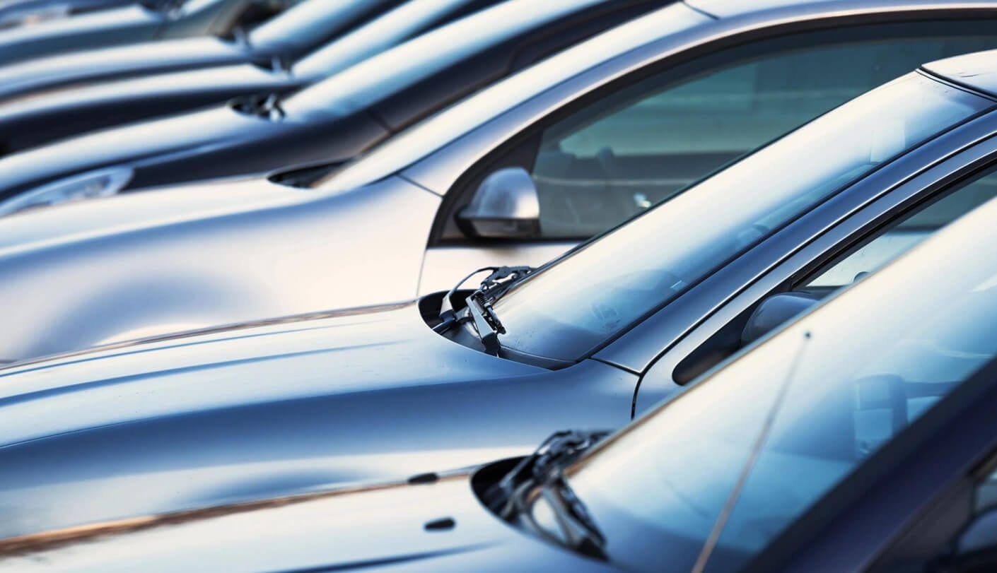 A row of silver cars parked in a lot.