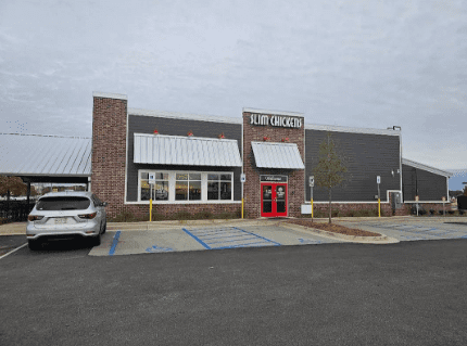 A large brick building with two cars parked in front of it.