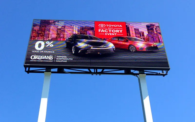Billboard advertising a car factory sale with a black car and cityscape background.