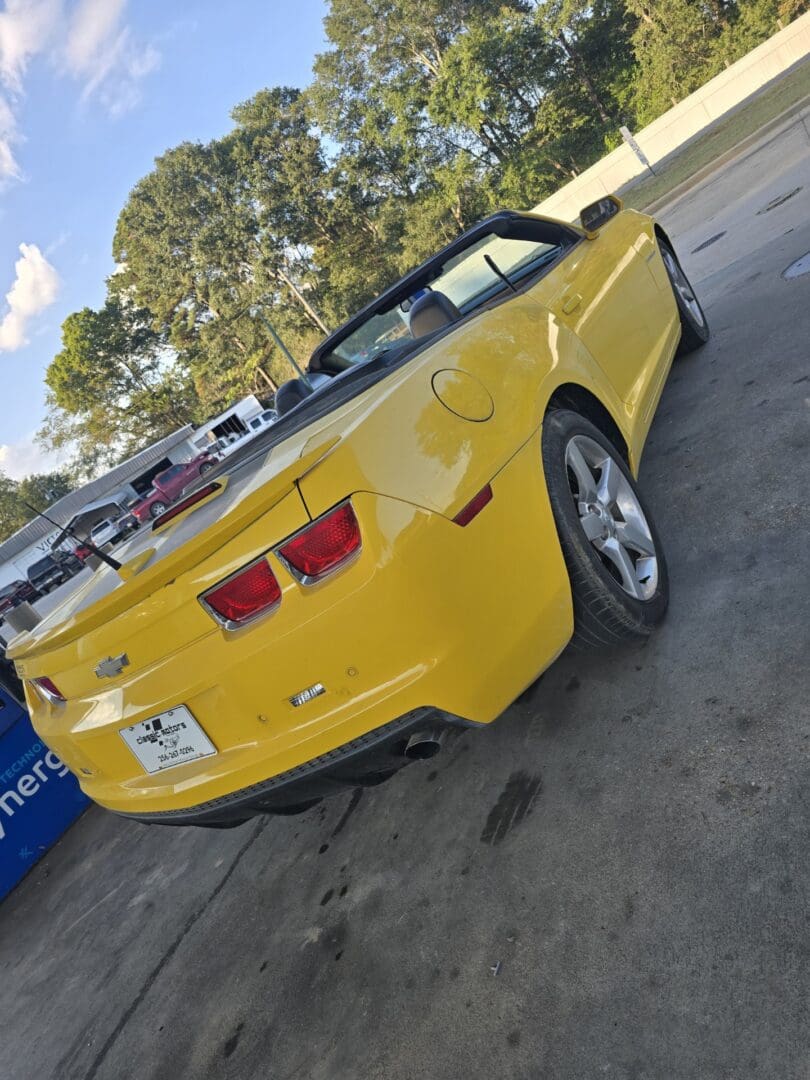 Yellow convertible sports car parked outdoors on a sunny day.