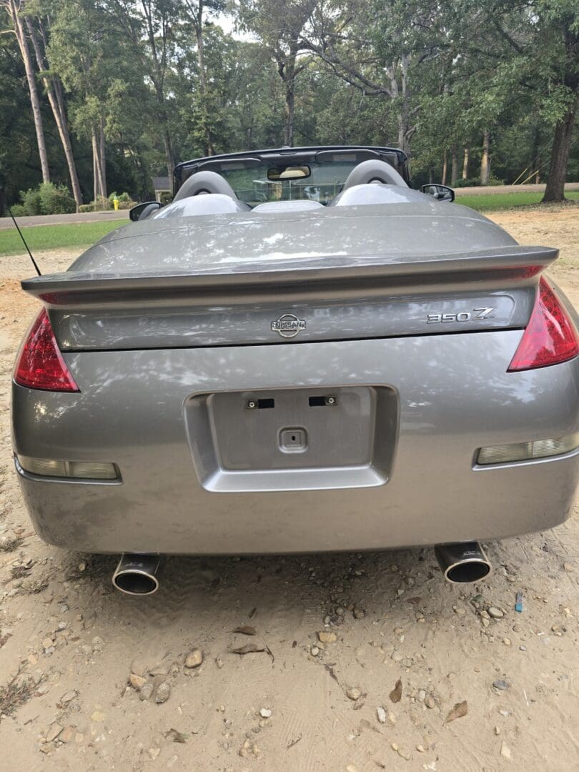 Rear view of a gray sports car with dual exhausts and spoiler.