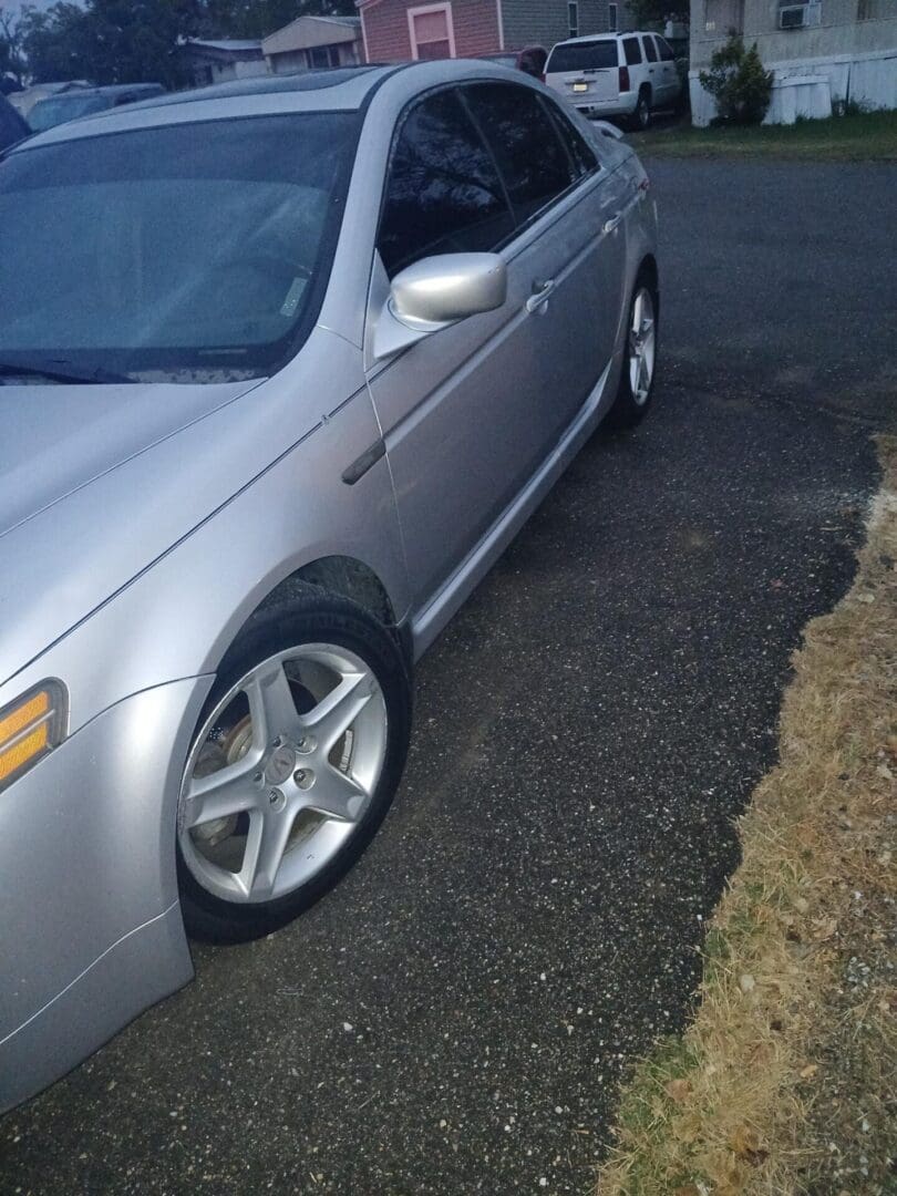 Silver car parked on a dark asphalt surface next to a gravel area.